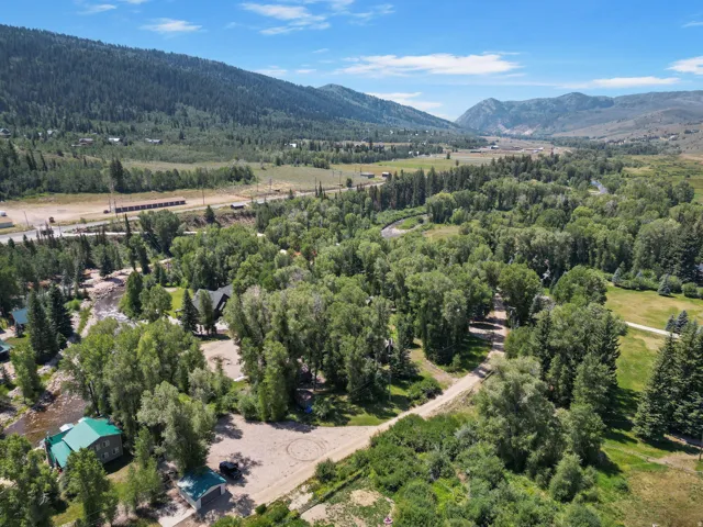 Expansive natural landscape featuring lush green trees, a winding river, and distant mountains under a blue sky