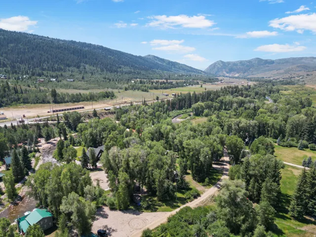 Expansive aerial perspective showcasing a mountainous landscape with a river and abundant mature trees