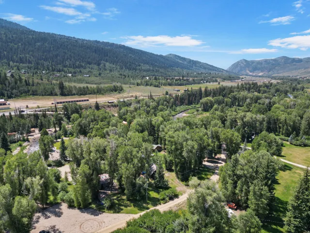 Expansive landscape featuring extensive tree coverage, a meandering river, and distant mountains