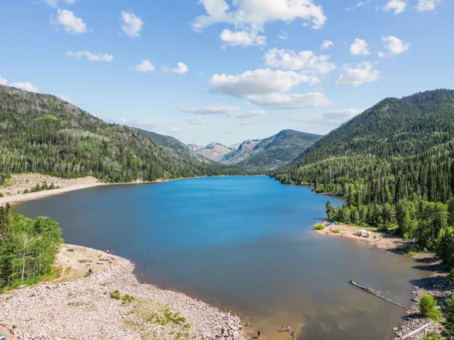 Expansive lake surrounded by forested mountains and clear skies