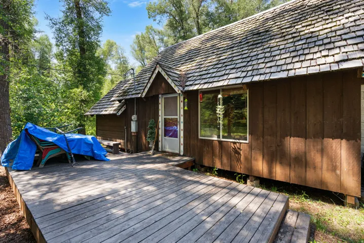 Wood-sided dwelling featuring a cedar shake roof, wood deck, and a prominent front entrance with a small covered porch