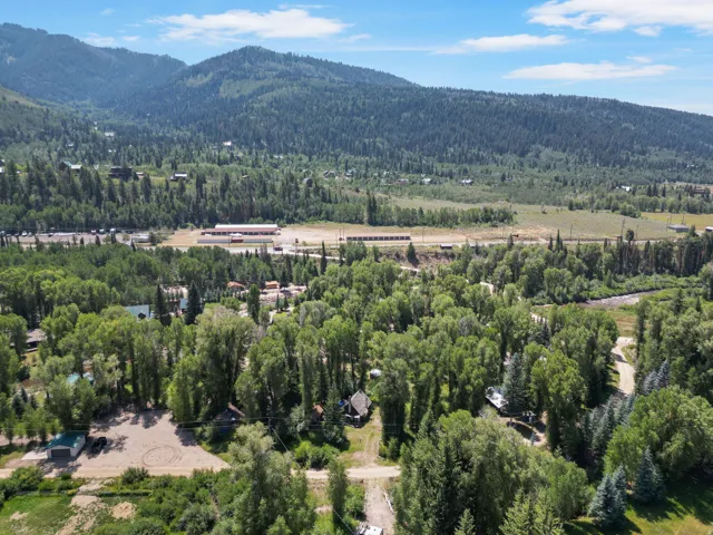 Expansive natural setting featuring dense tree cover, mountainous backdrop, and a winding waterway