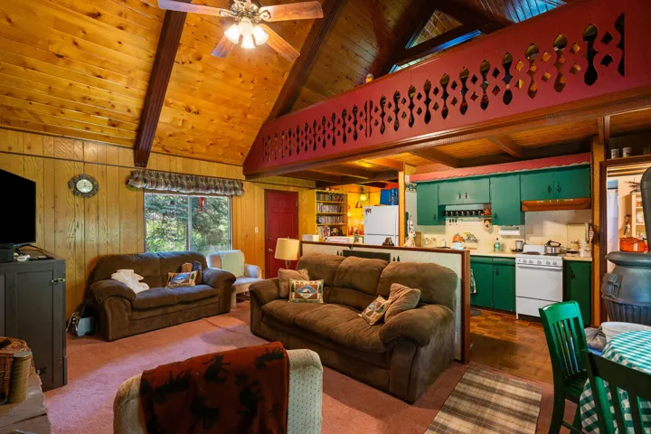 Vaulted wood-paneled ceilings, a decorative loft railing, and a functional kitchen with green cabinetry