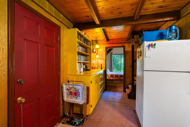 Interior space featuring a red paneled door, wood-paneled walls, and wood-beam ceilings