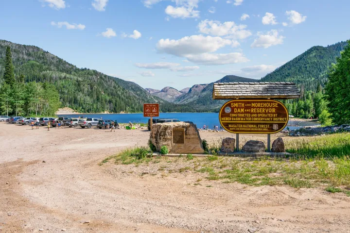 Scenic lakefront parking area with direct access to pristine alpine lake surrounded by forested mountain peaks