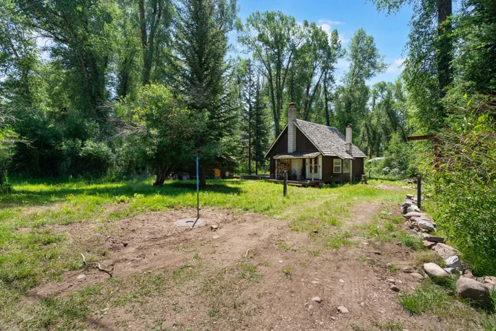 Charming cabin-style residence featuring a prominent stone chimney and a cedar shingle roof