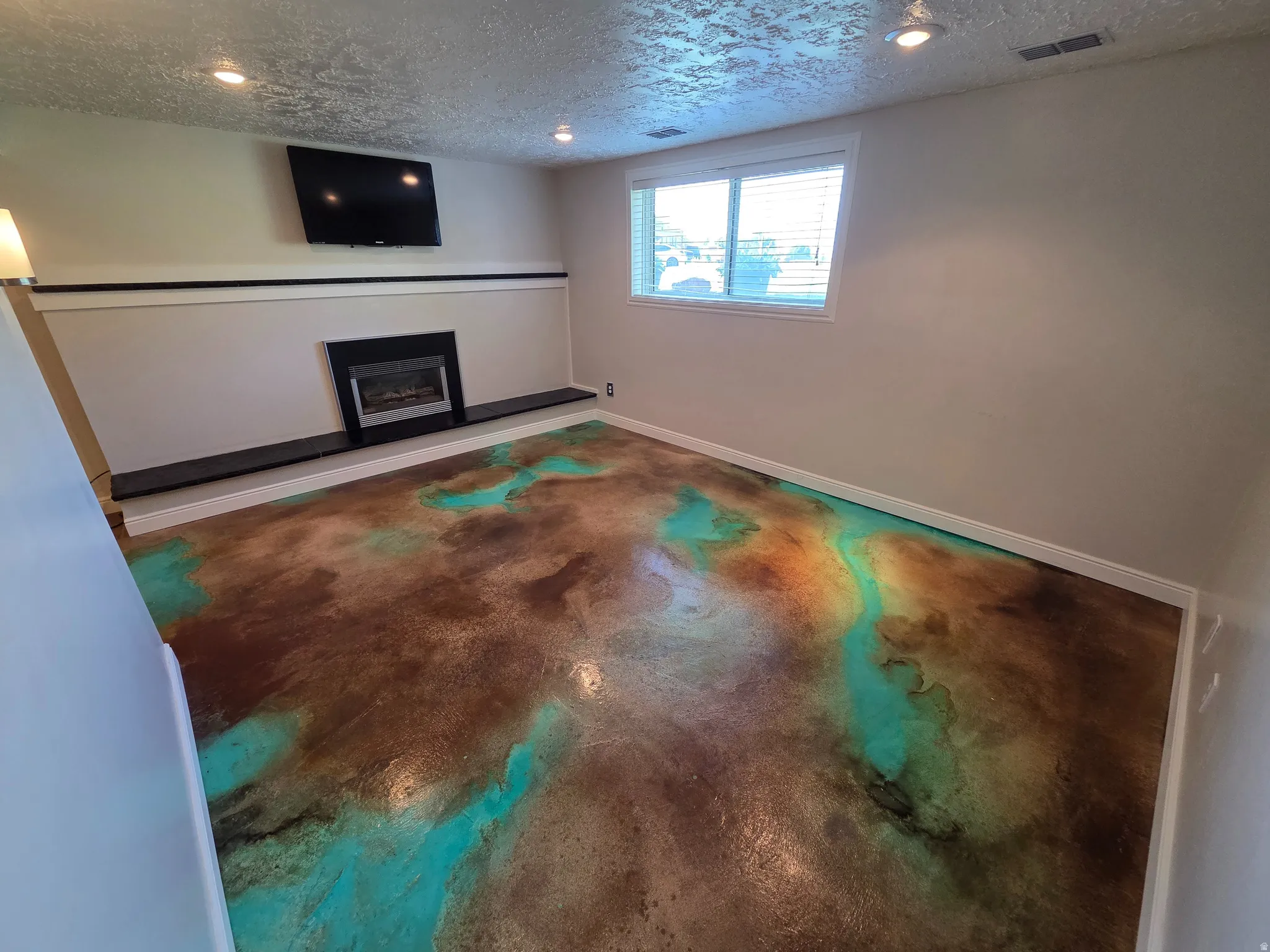 Distinctive flooring featuring a brown and teal stained concrete finish
