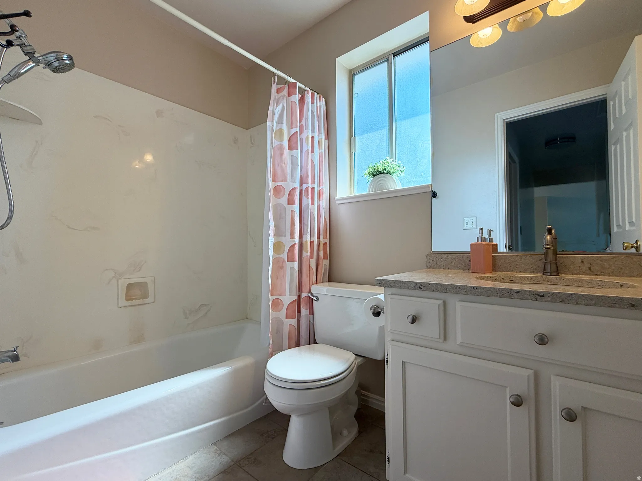 Bathroom featuring a single vanity with a granite-look countertop, white cabinetry with round silver-toned hardware, a fixed mirror, and an overhead light fixture