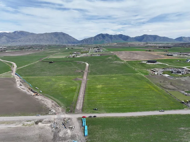 Expansive undeveloped land with a mountain backdrop, featuring visible infrastructure development and clearings