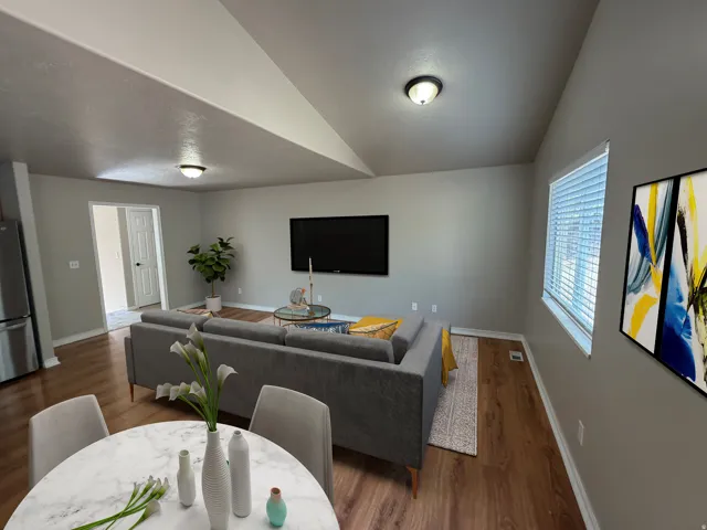 Spacious living area featuring wood-finish flooring, recessed lighting, and a window with blinds