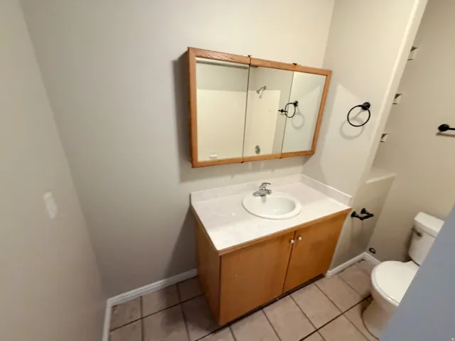 Vanity with wood-finish cabinetry, integrated sink, and laminate countertop