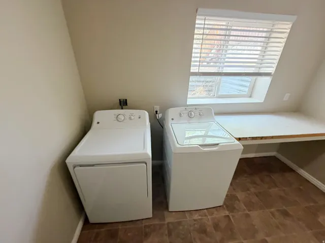 Sloped ceiling room featuring a built-in countertop, window with blinds, and brown tile flooring