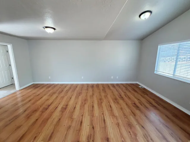 Wood-finish flooring, neutral wall tones, white trim, and a window with blinds