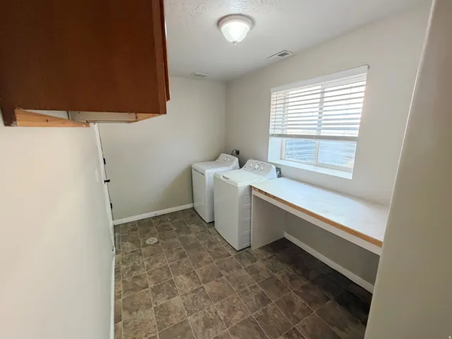 Laundry room featuring a built-in folding counter, window with blinds, overhead light fixture, and tiled flooring
