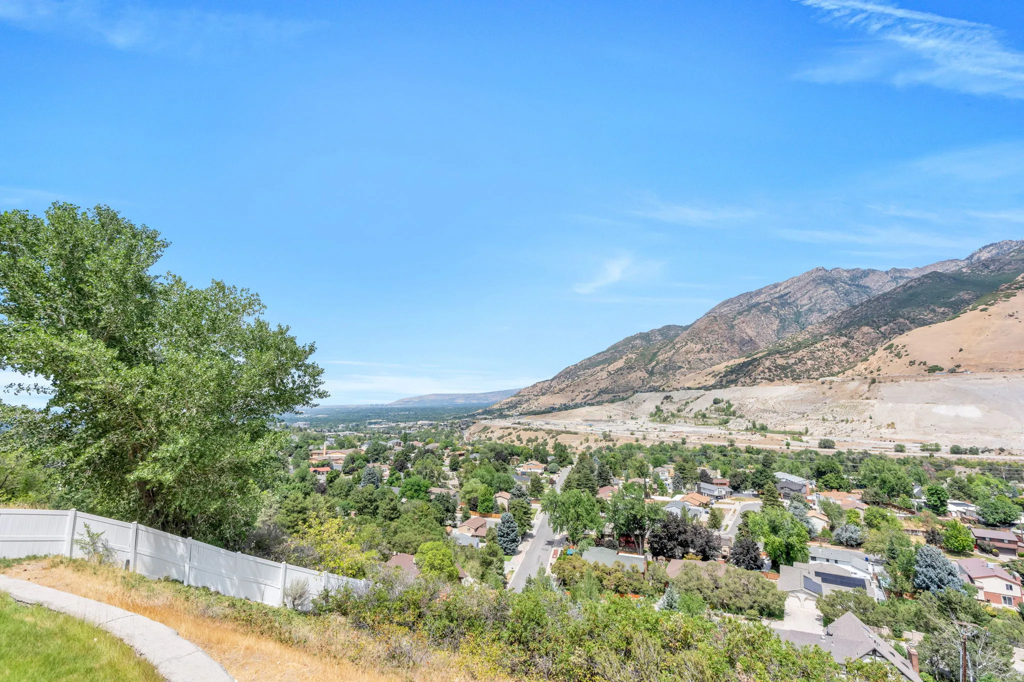 Expansive territorial scenery featuring a distant valley, mountain range, and residential rooftops
