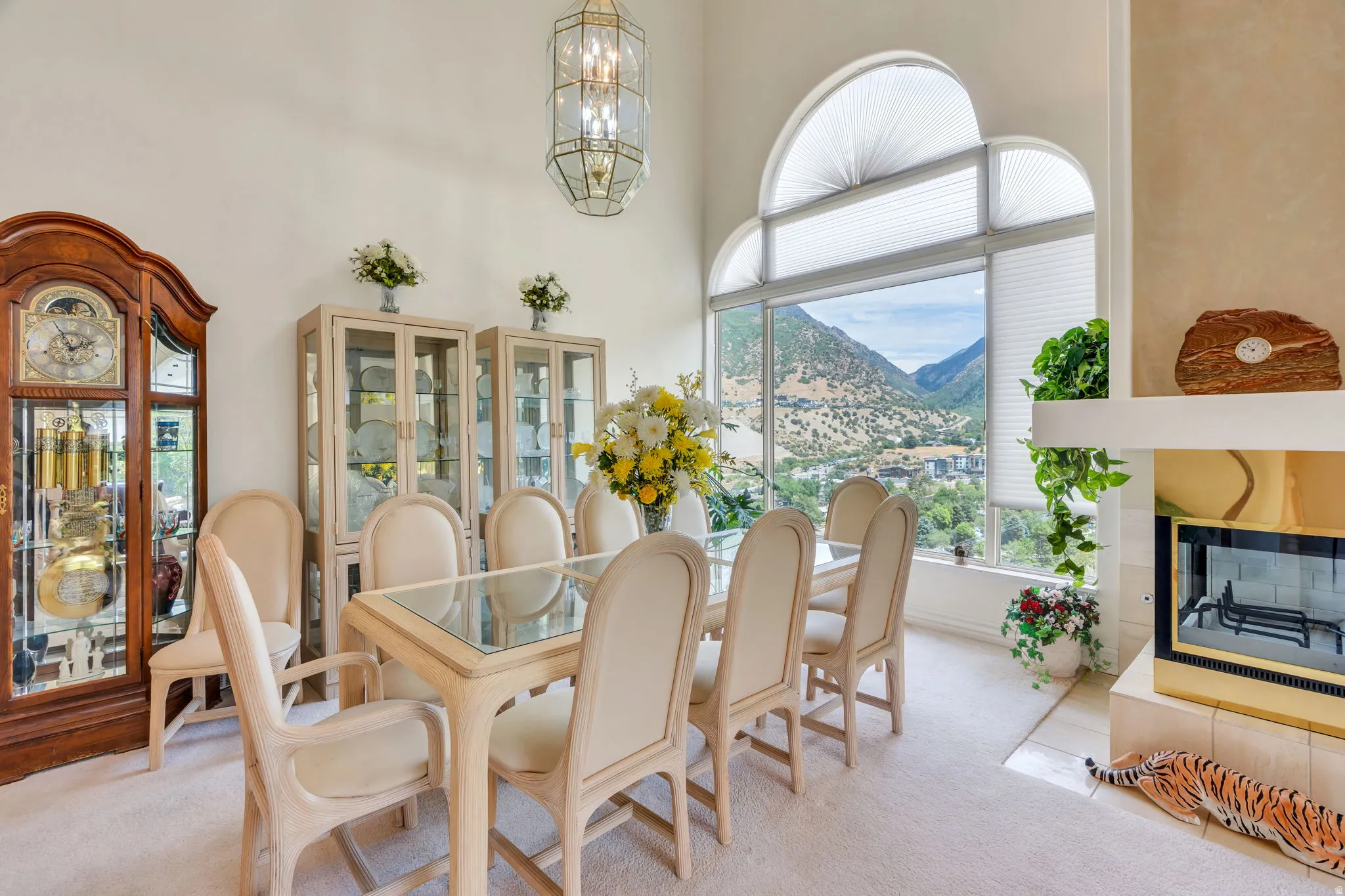 Vaulted ceiling dining area featuring a fireplace with a stone mantel, large arched windows, and a hanging chandelier
