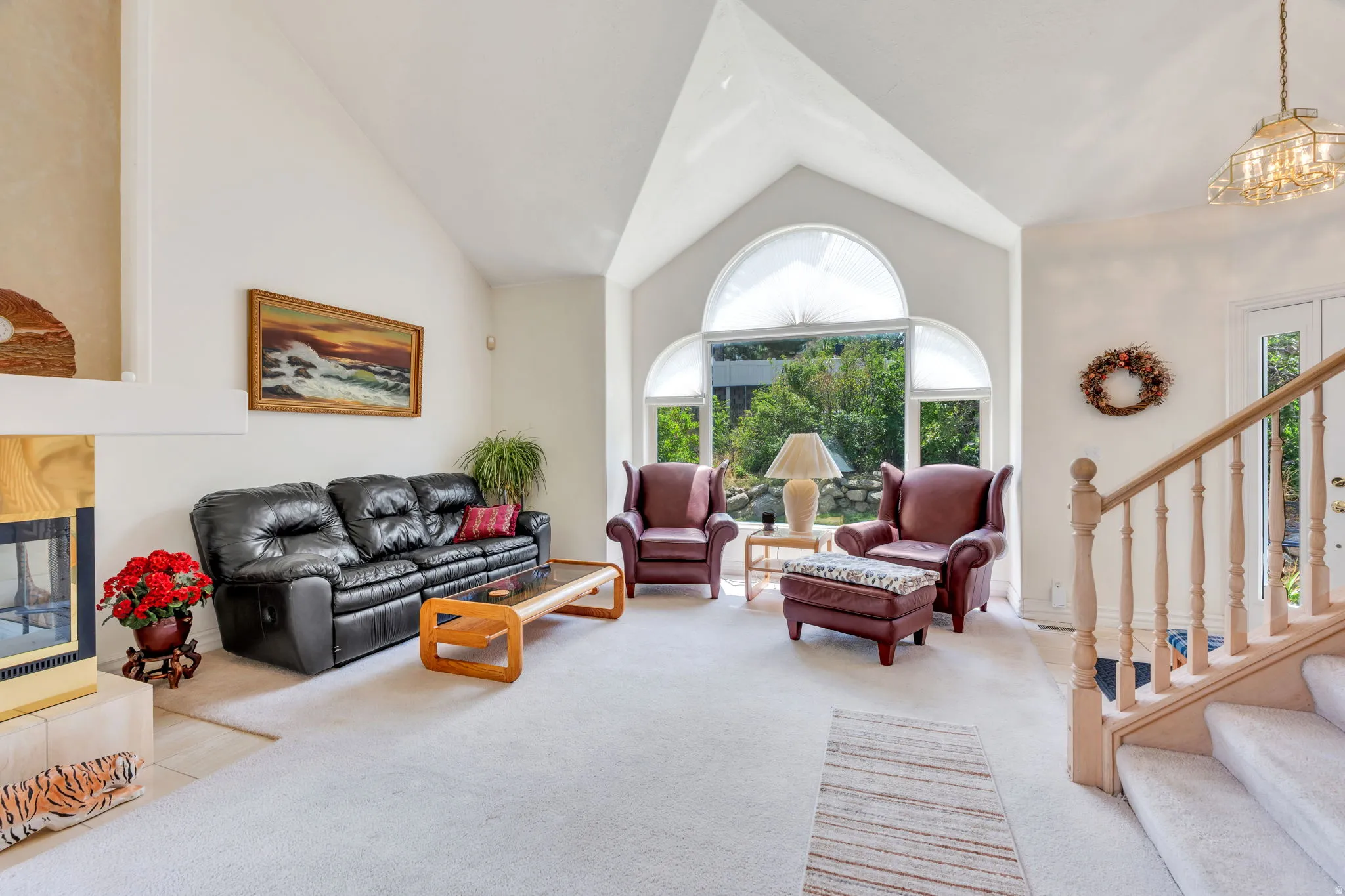 Living area featuring vaulted ceilings, a large arched window, and carpet flooring