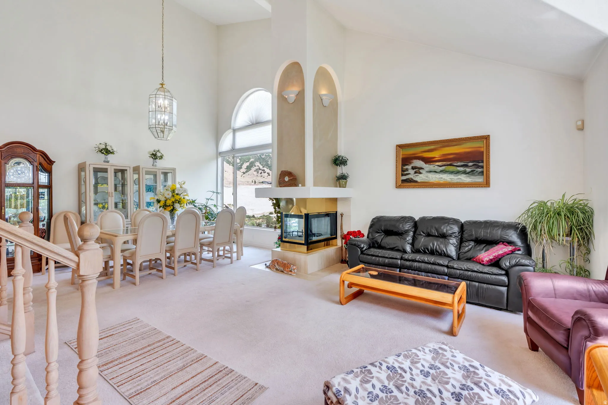 Open-concept living area featuring vaulted ceilings and a built-in fireplace with a stone hearth
