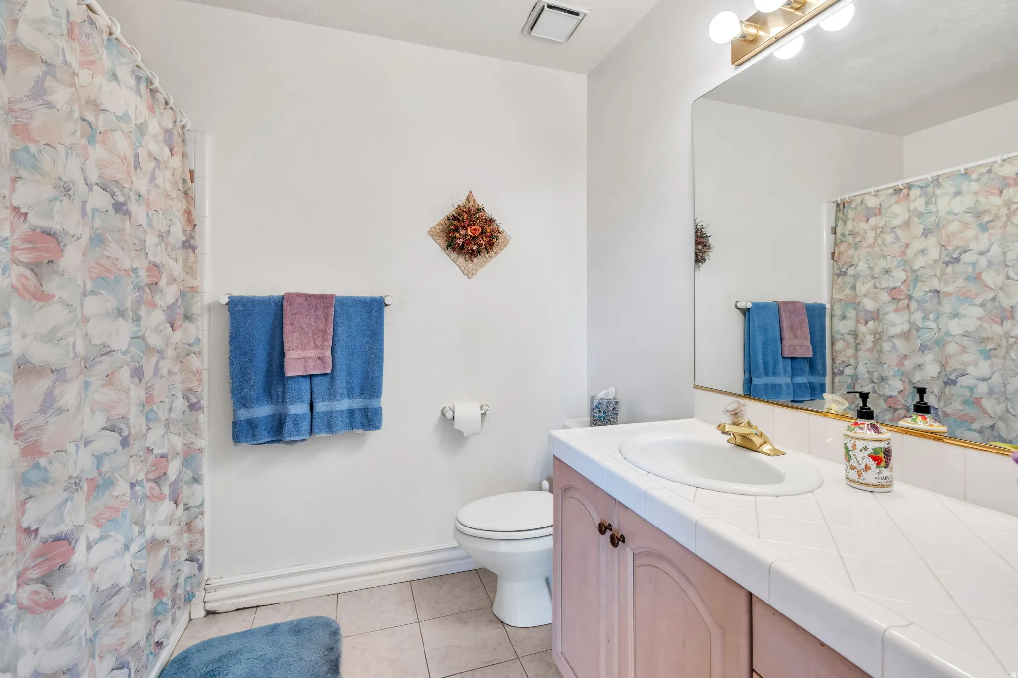 Spa-inspired bathroom featuring a pink vanity with white quartz countertop, large framed mirror, and polished chrome fixtures