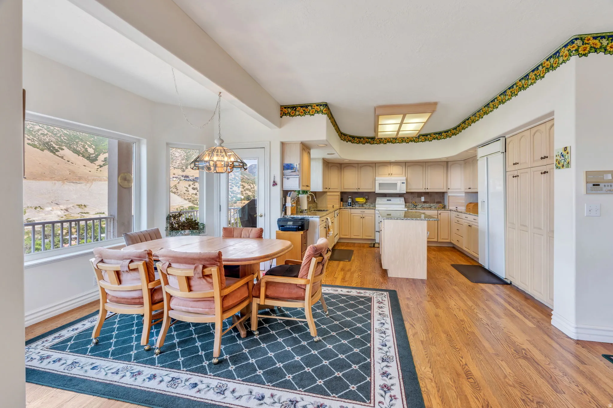 Open-concept kitchen and dining area featuring wood-finish flooring, light-toned cabinetry, a central island, and a built-in refrigerator