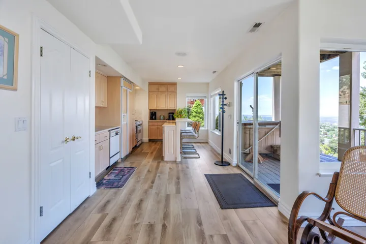 Wood-finish flooring, light wood cabinetry, white appliances, and sliding glass door