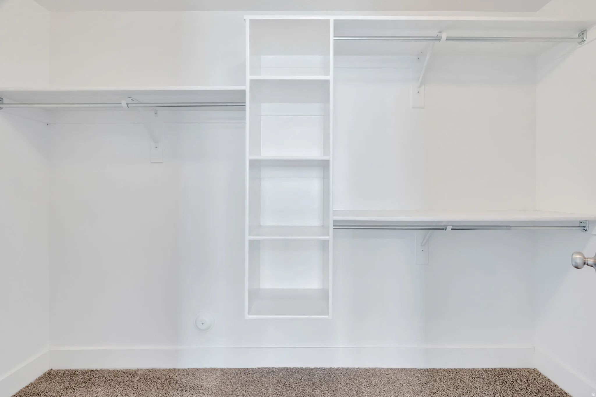 Walk-in closet featuring built-in shelving, multiple hanging rods, and neutral-toned carpeting