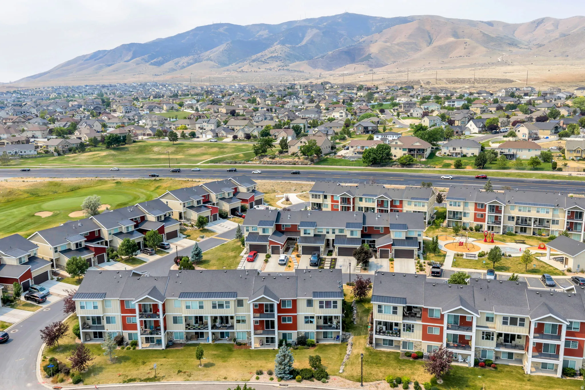 Expansive community featuring multi-story residential buildings with balconies, a playground area, and mature landscaping
