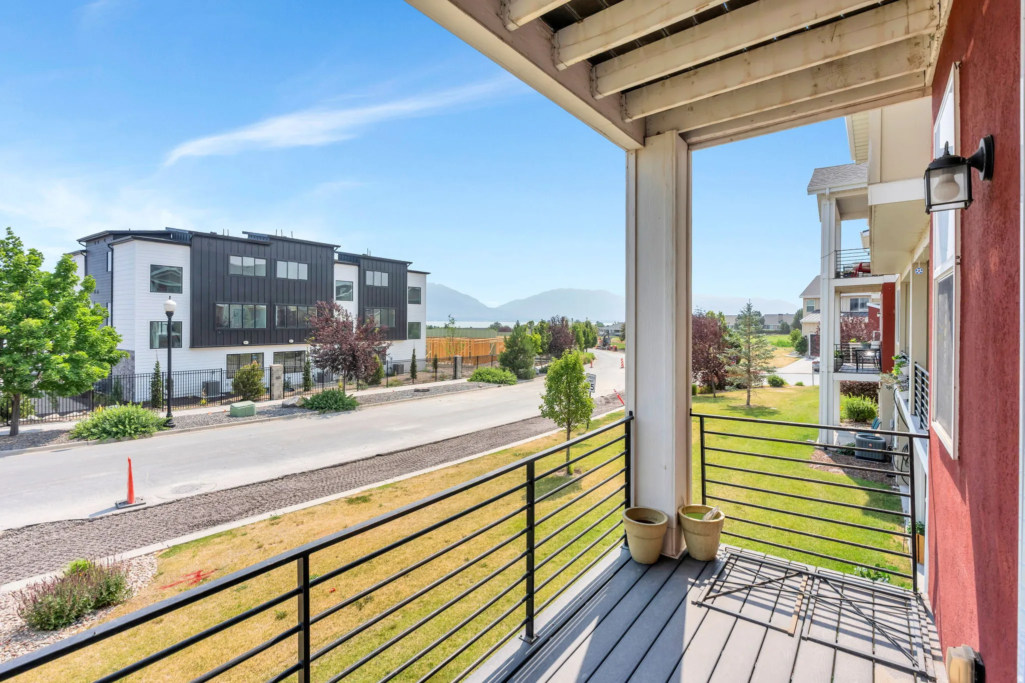Private balcony featuring composite decking, black metal railings, and an exterior wall light