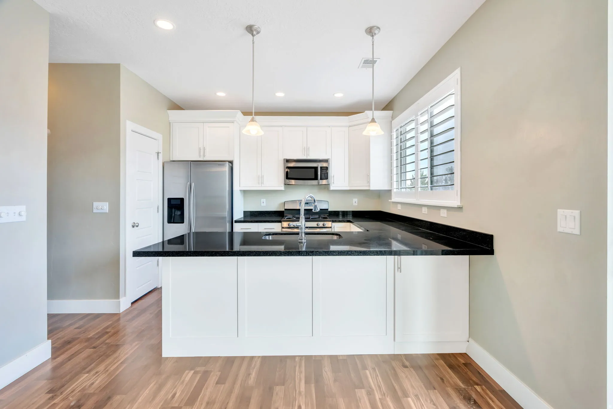 Kitchen featuring wood-finish flooring, white cabinetry, dark countertops, and stainless steel appliances