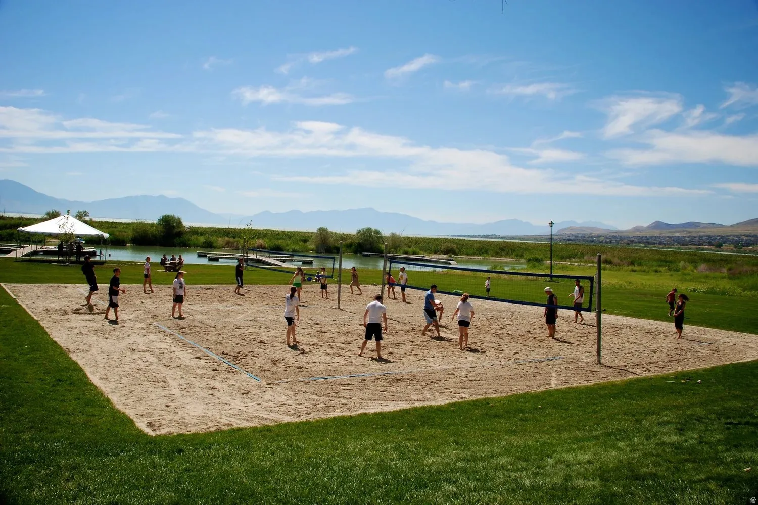 Sand volleyball court with a net, bordered by green grass