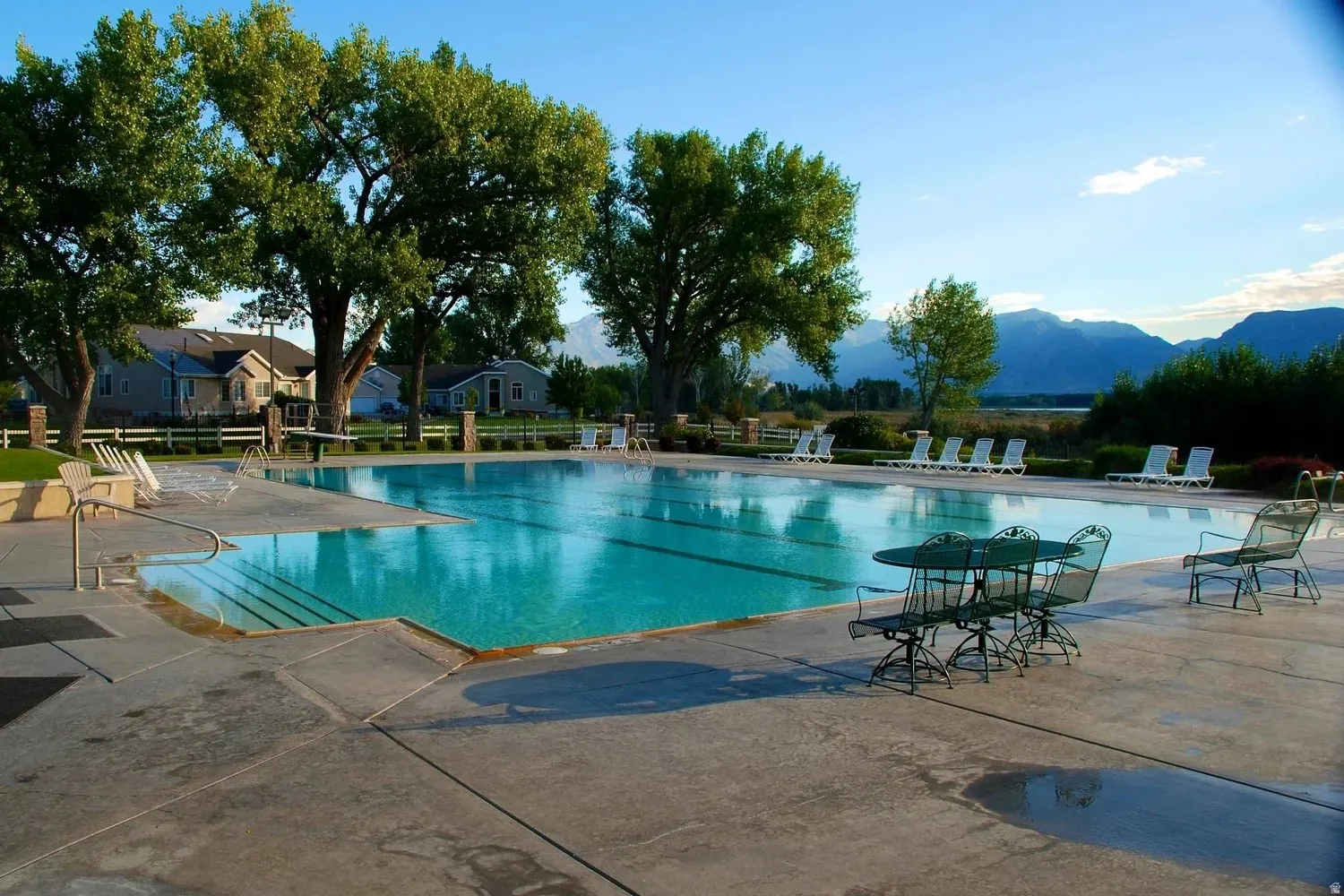 Expansive outdoor swimming pool with integrated lane lines, surrounded by a concrete deck and mature trees