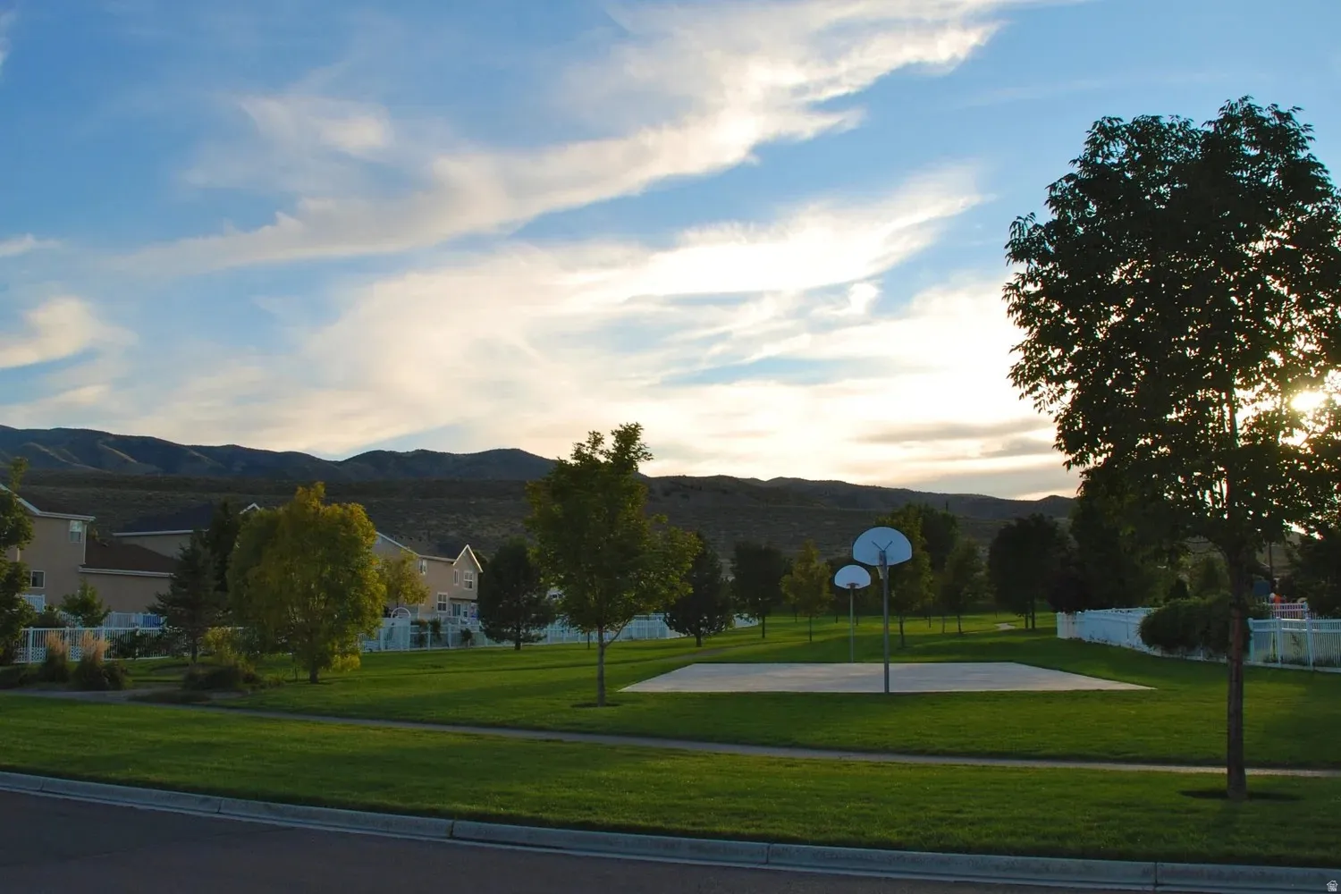 Community green space featuring an asphalt sports court with two basketball hoops