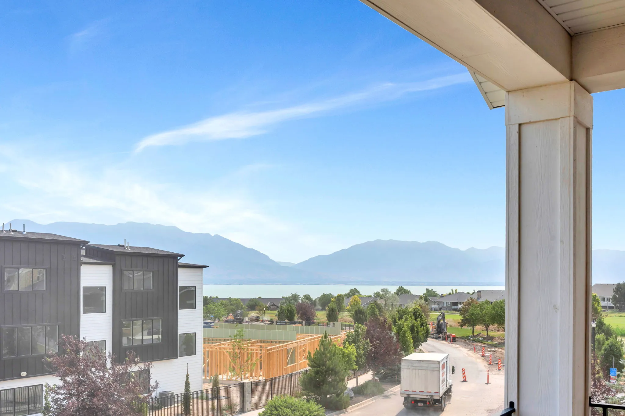 Balcony off primary bedroom featuring a solid column and soffit, with distant mountains and a body of water visible
