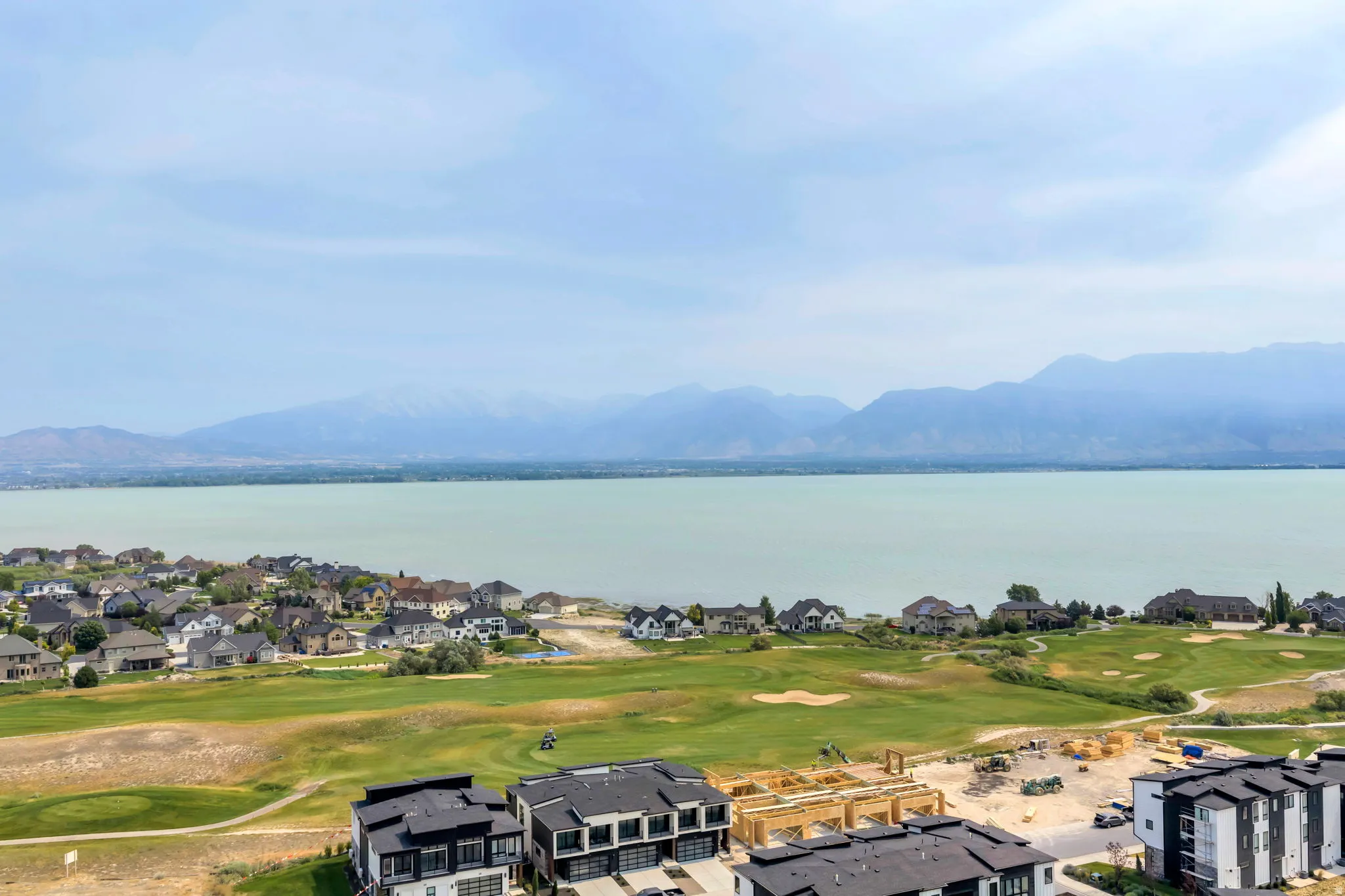 Panoramic water body and mountain backdrop with a golf course and residential properties