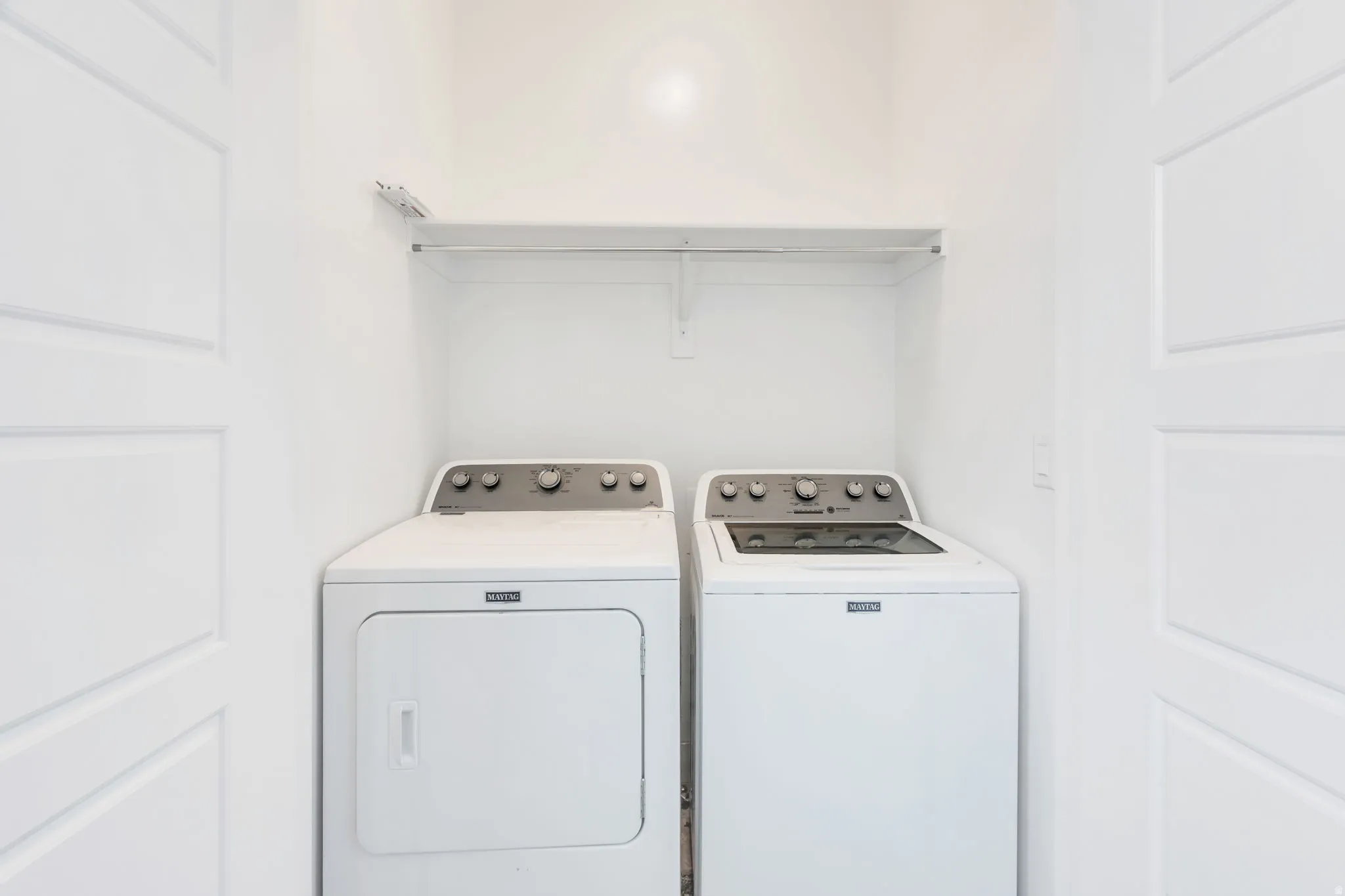 Dedicated laundry area featuring a washer and dryer set, integrated shelving, and panel doors