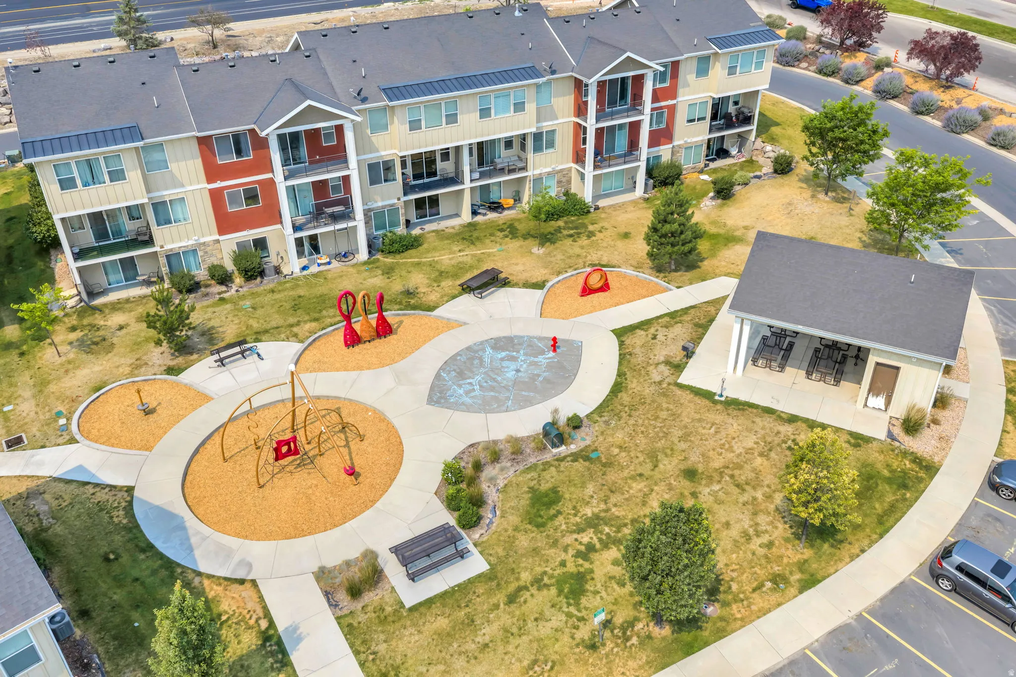 Multifamily residential building featuring balconies, a covered outdoor gathering area, and a playground with benches and various play structures