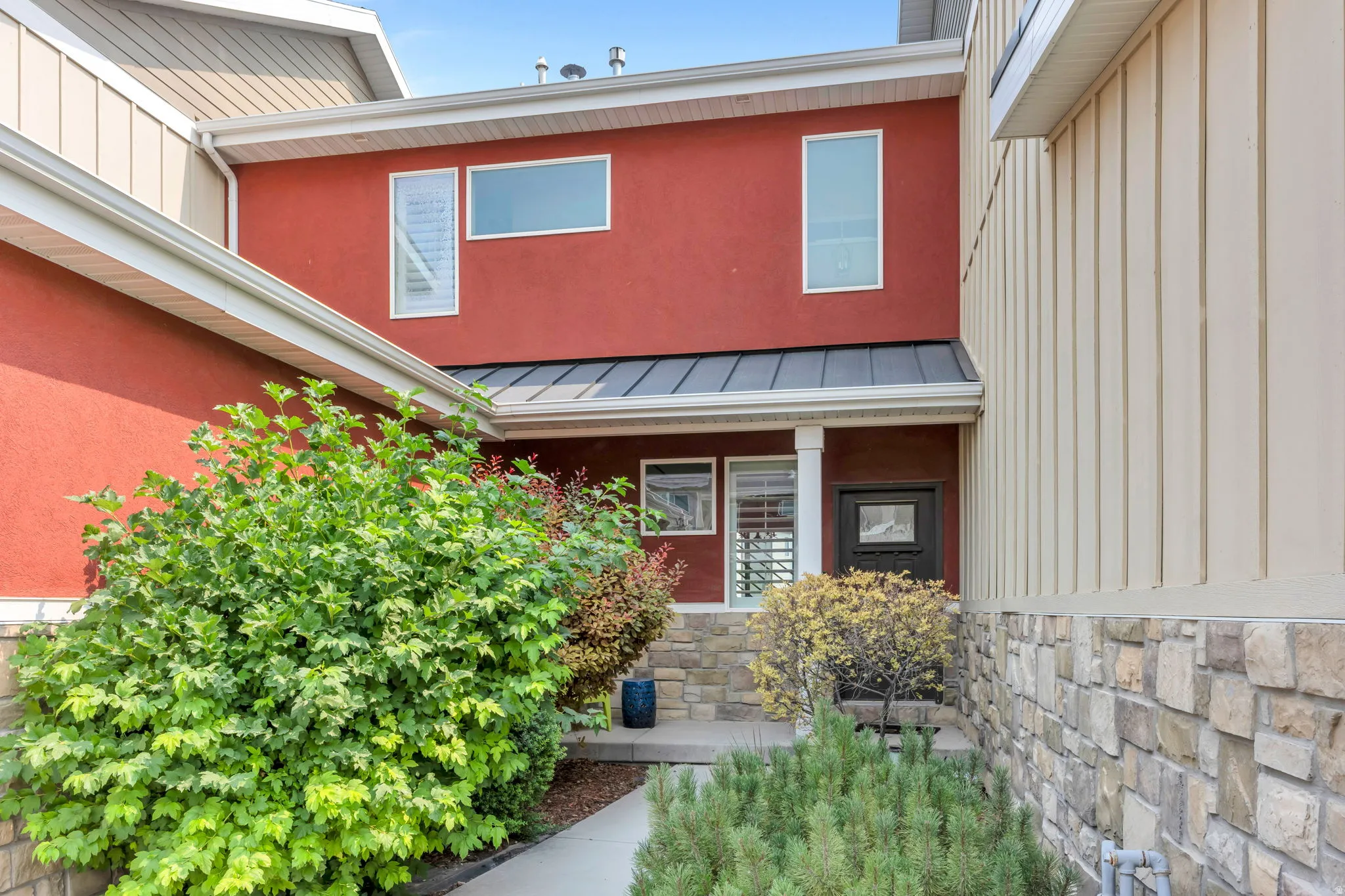 Contemporary architecture featuring red stucco and cream vertical siding with stone accents