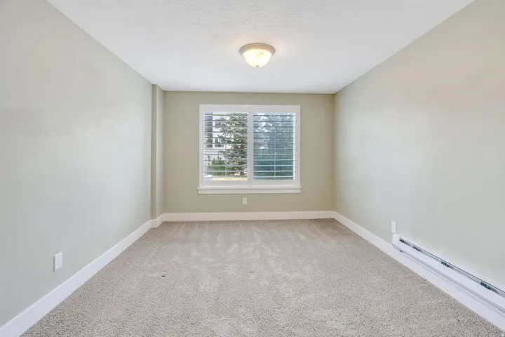Room featuring neutral carpeting, light-toned walls, and a window with white louvered blinds