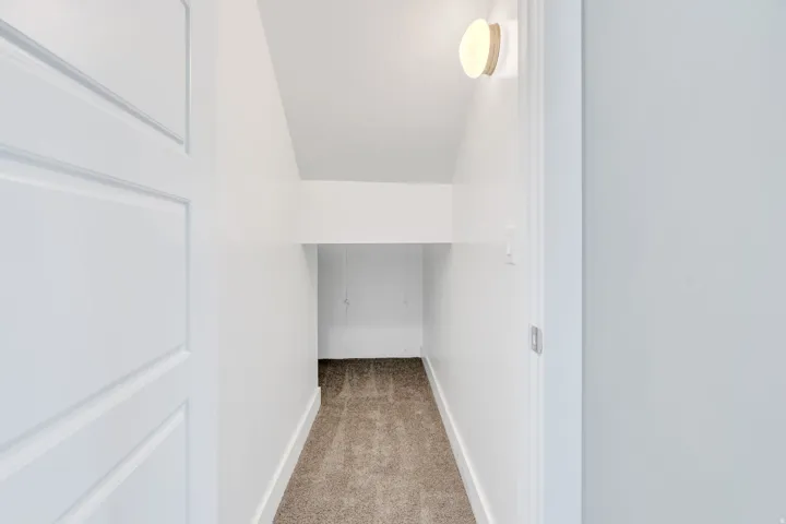 Recessed storage area featuring neutral carpet flooring and a contemporary wall sconce. Excellent space for additional storage while Harry is away at Hogwarts.
