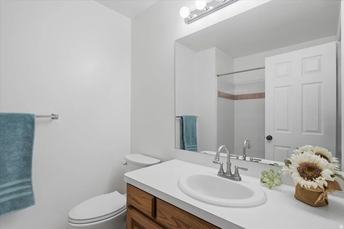 Guest Bathroom featuring a wood-finish vanity with a white countertop and an integrated oval sink