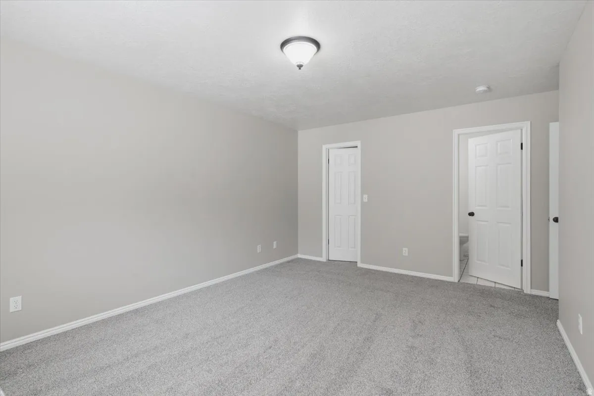 Upstairs 2nd Master, Spacious interior room featuring light brown walls and plush gray carpeting