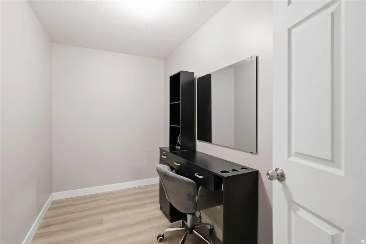 Compact room with light-toned walls and wood-finish flooring. Multi purpose space: Storage, vanity, office space.