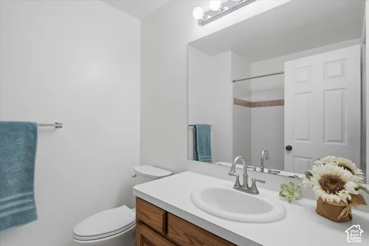 Guest Bathroom featuring a wood-finish vanity with a white countertop and an integrated oval sink