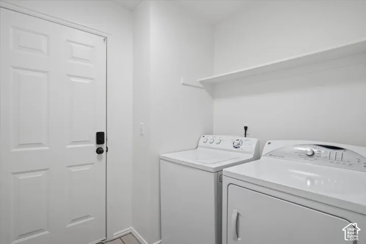 Dedicated laundry area featuring a white six-panel door, light-colored walls, and an overhead storage shelf