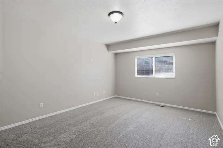 Spacious room featuring neutral carpeting and light brown wall paint