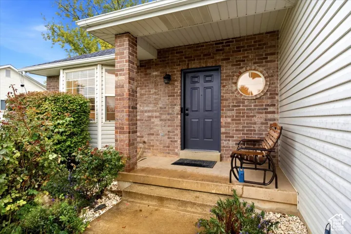 Covered entryway featuring a brick facade, circular accent window, multi-panel front door, and concrete porch steps