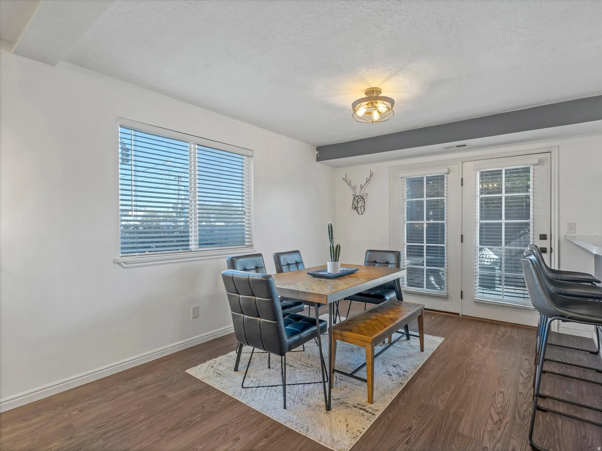 Dining area featuring wood-finish flooring, a large window with blinds, and double French doors providing exterior access