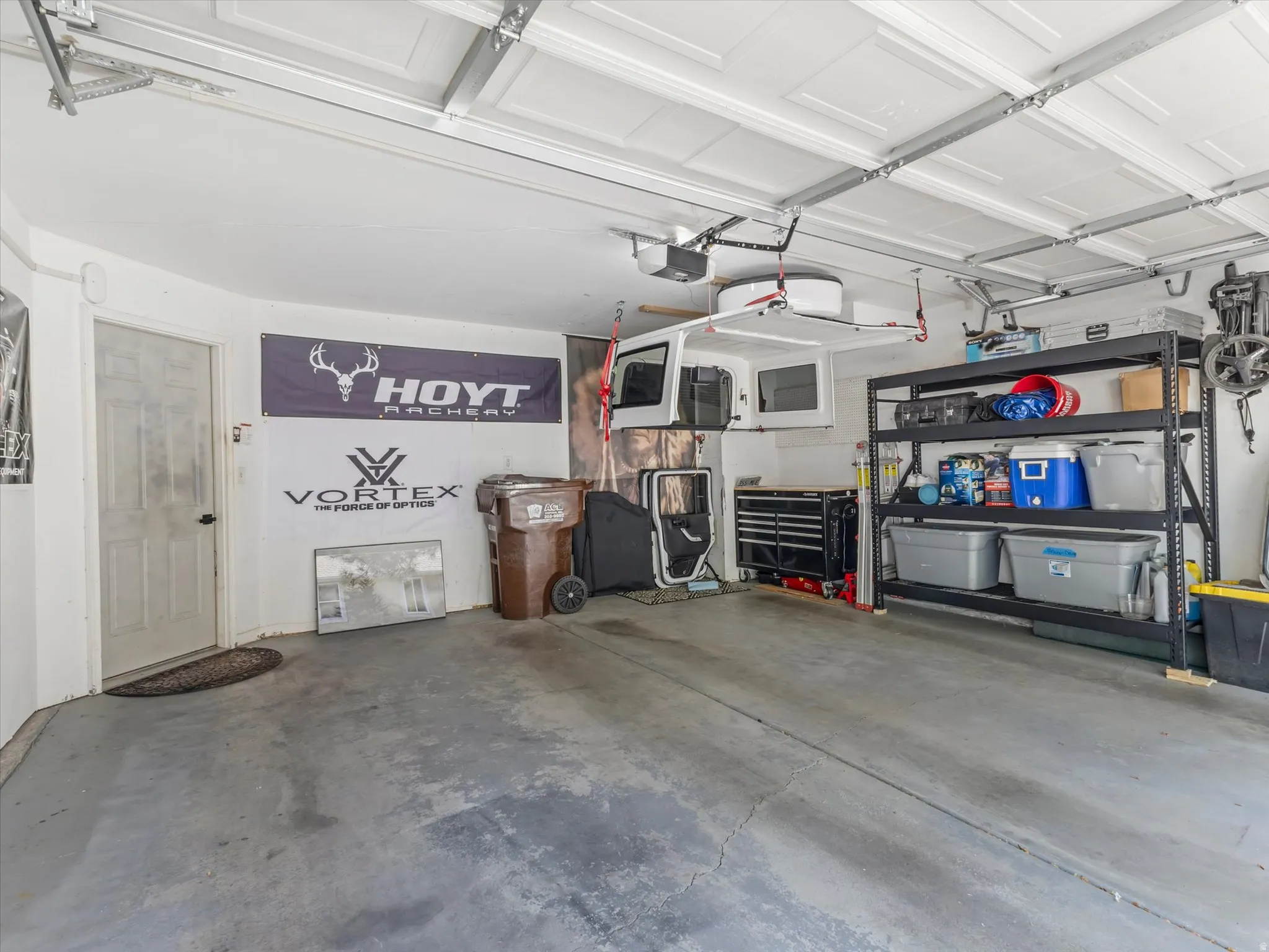 Two-car garage featuring a painted concrete floor, white walls, and a white paneled garage door