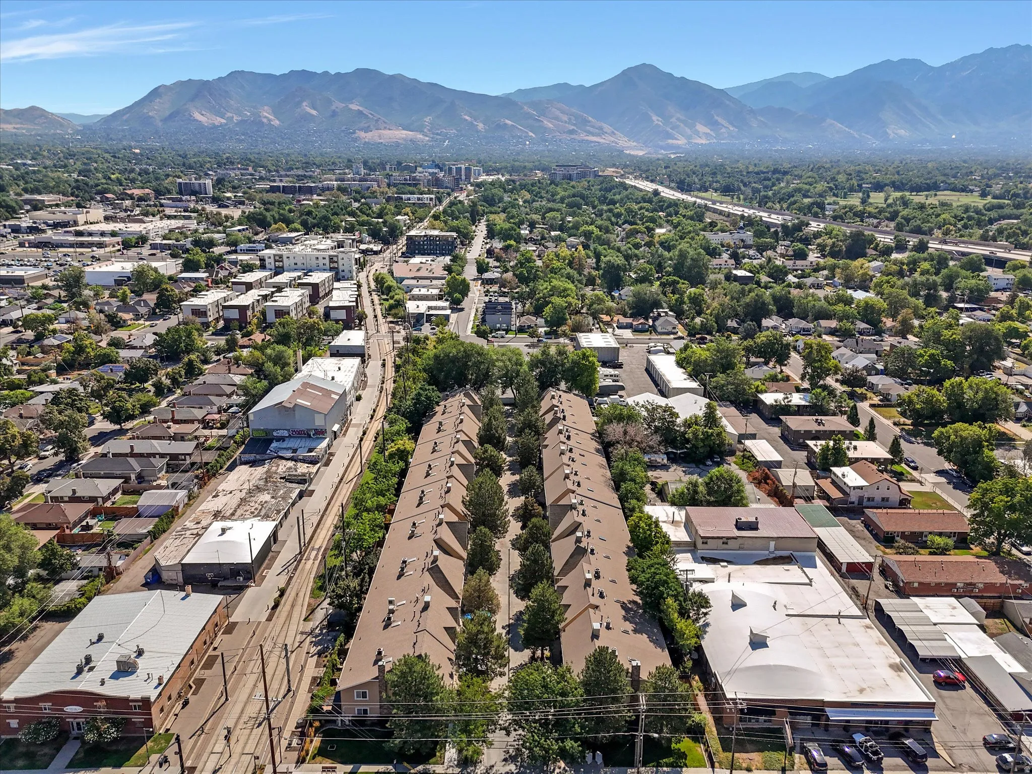 Aerial perspective showcasing a residential development with rows of attached housing units, each featuring a brown shingle roof