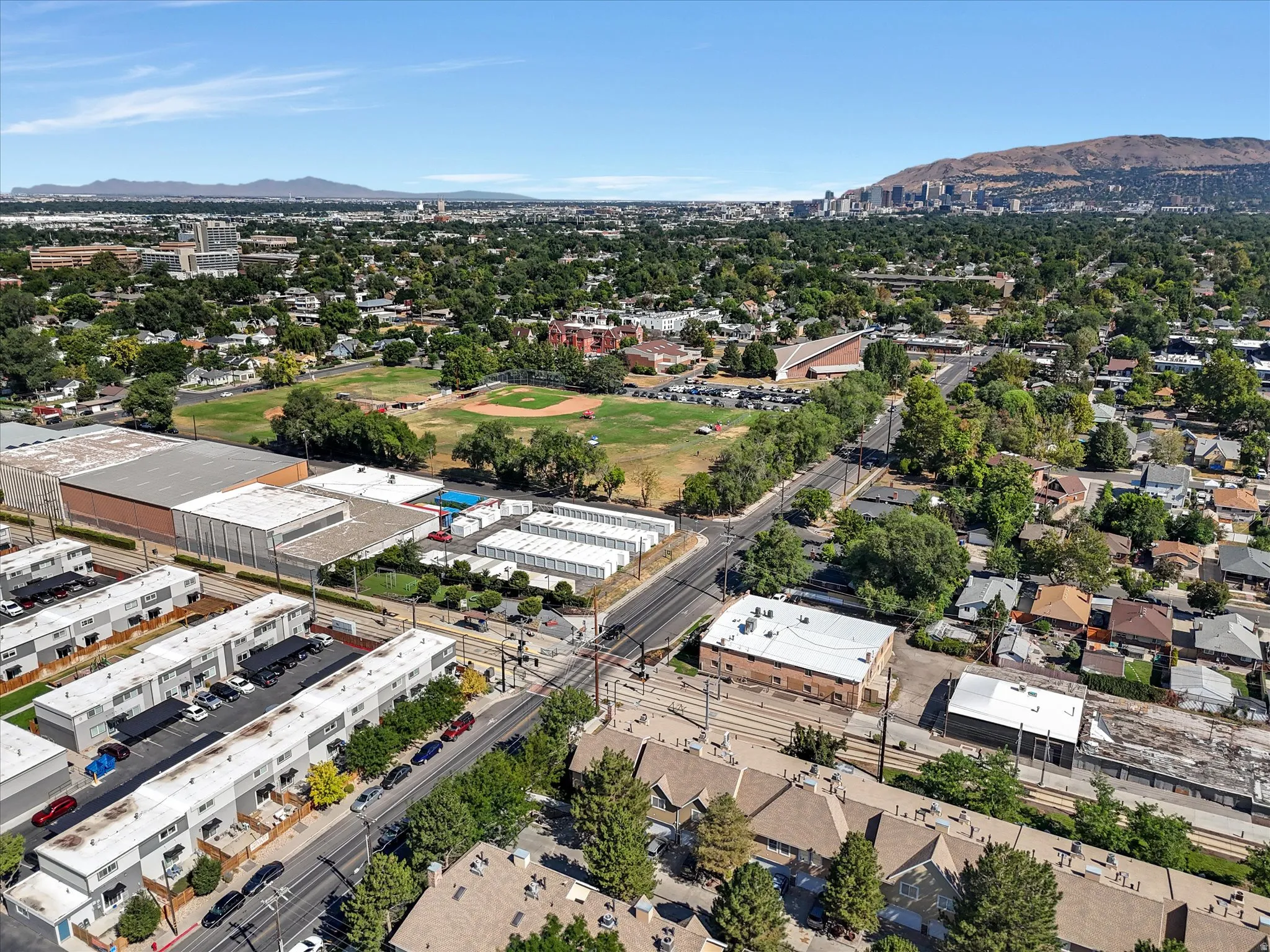 Expansive aerial overview showcasing a diverse urban landscape with residential properties, commercial structures, and green spaces
